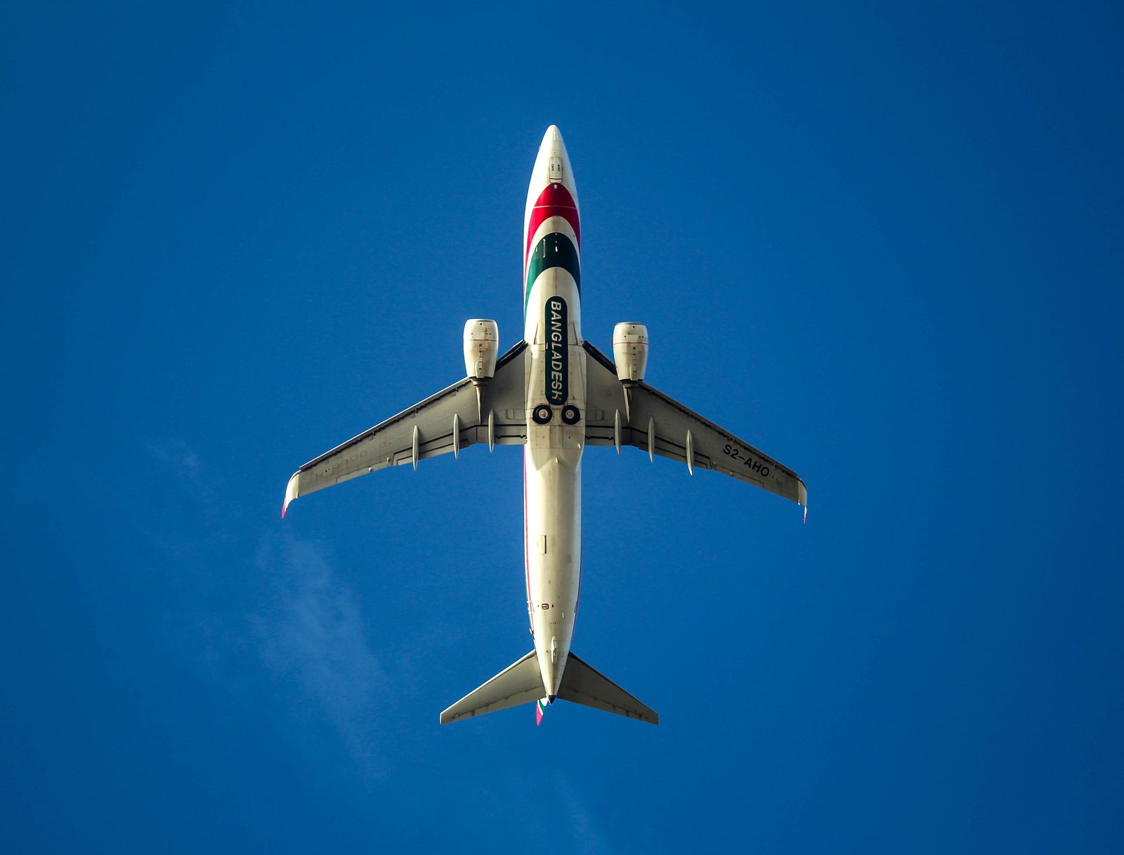 A Biman Bangladesh Airlines aircraft captured mid-flight against a clear blue sky.